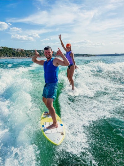 two people riding a wave on a surf board